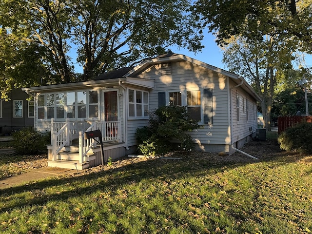 bungalow-style house featuring a sunroom, a front yard, and central AC unit