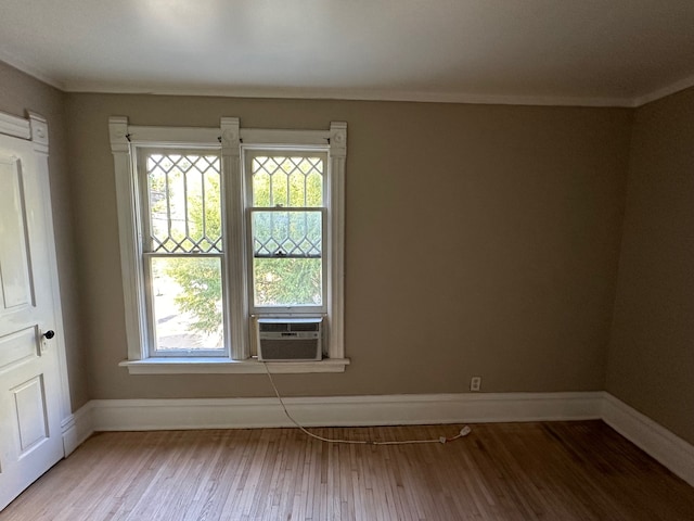 spare room featuring wood-type flooring, cooling unit, and ornamental molding