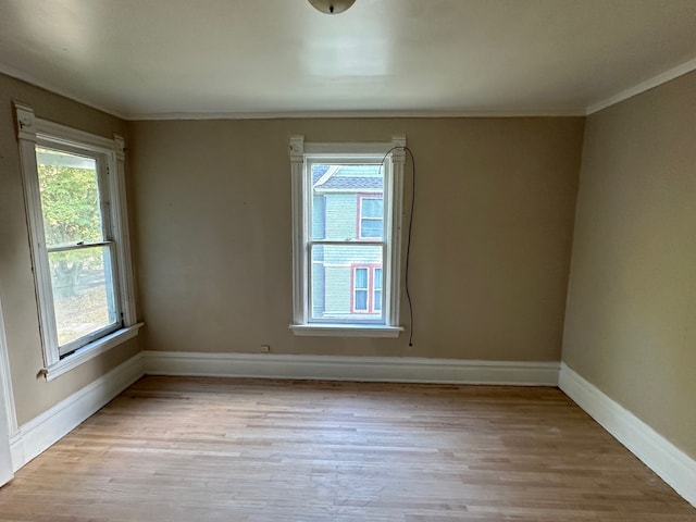 spare room featuring ornamental molding and light hardwood / wood-style flooring