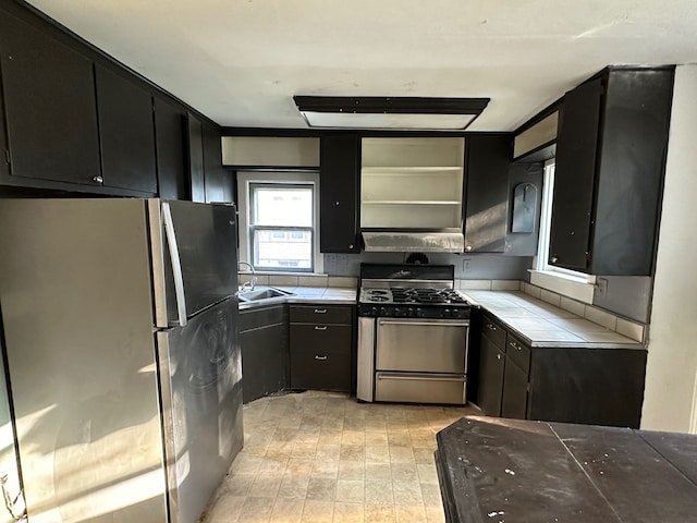 kitchen with sink, stainless steel gas range oven, and fridge