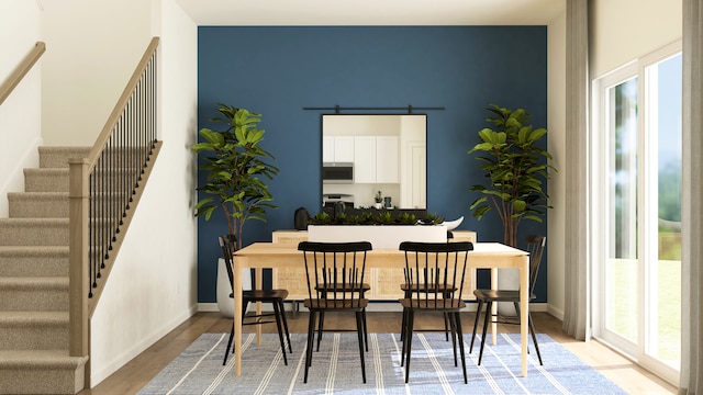 dining room with light hardwood / wood-style floors, a healthy amount of sunlight, and a barn door