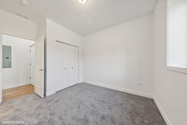 unfurnished bedroom with light carpet, a closet, and electric panel