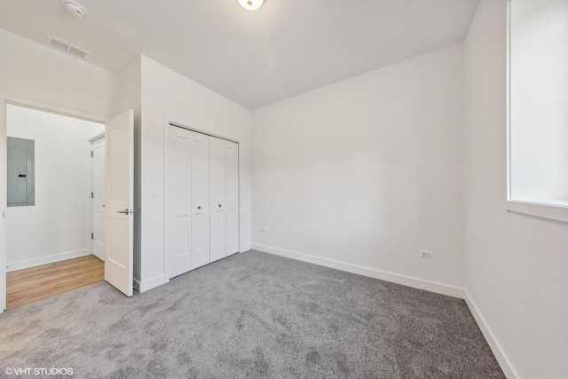 unfurnished bedroom featuring carpet, visible vents, a closet, electric panel, and baseboards