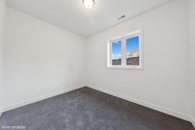 empty room with baseboards, dark colored carpet, and visible vents