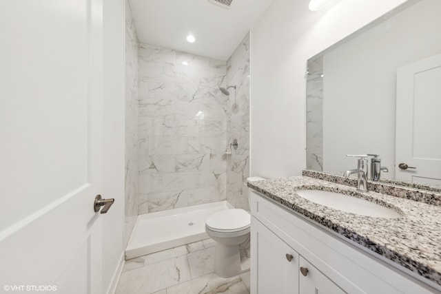 bathroom featuring vanity, toilet, and tiled shower