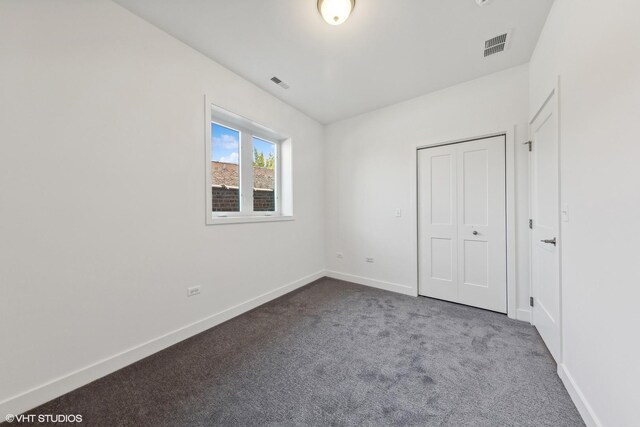 unfurnished bedroom with dark carpet, visible vents, and baseboards
