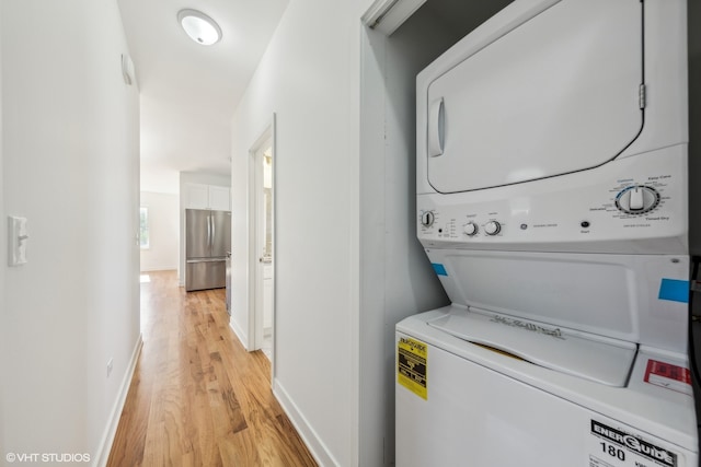 laundry room featuring stacked washer and dryer and light wood-type flooring