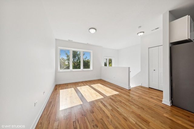 empty room featuring baseboards, visible vents, and light wood-type flooring