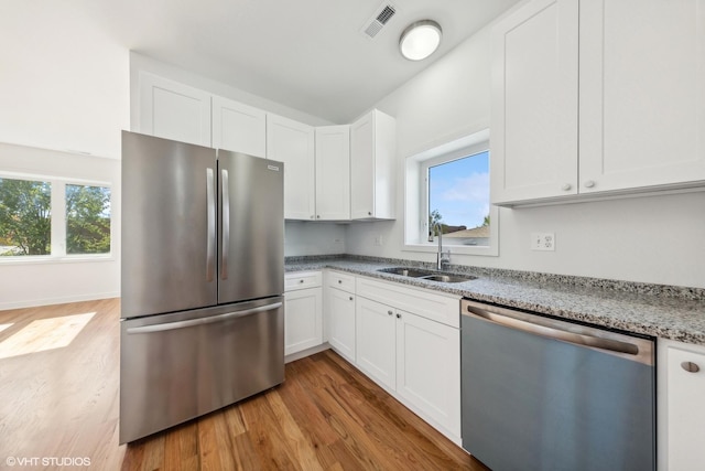 kitchen featuring wood finished floors, visible vents, stainless steel appliances, and a sink