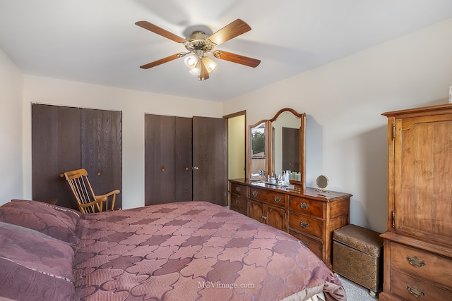 carpeted bedroom featuring ceiling fan and two closets