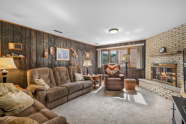 carpeted living room with wood walls and a brick fireplace