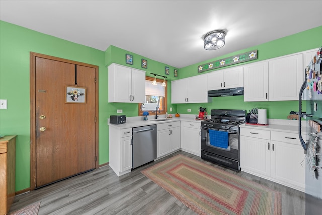 kitchen featuring black range with gas stovetop, sink, stainless steel dishwasher, white cabinetry, and light hardwood / wood-style floors