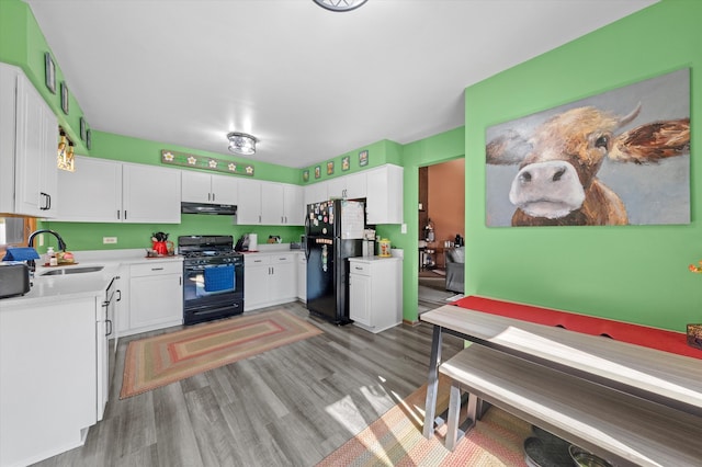 kitchen with light hardwood / wood-style flooring, white cabinetry, black appliances, and sink