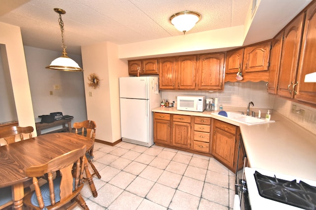 kitchen featuring decorative backsplash, hanging light fixtures, sink, a textured ceiling, and white appliances