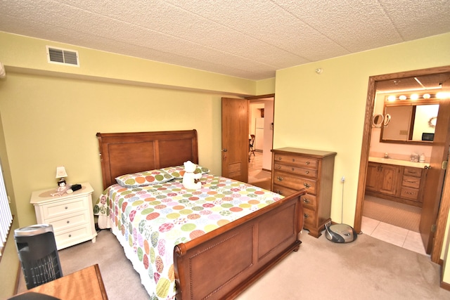 carpeted bedroom featuring a textured ceiling, ensuite bath, and sink