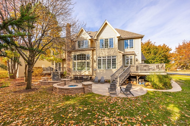 rear view of house featuring a lawn, a patio area, a wooden deck, and a fire pit