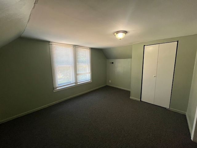 bonus room with dark carpet and lofted ceiling