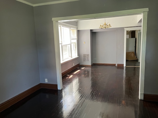 spare room with dark wood-type flooring, crown molding, and an inviting chandelier