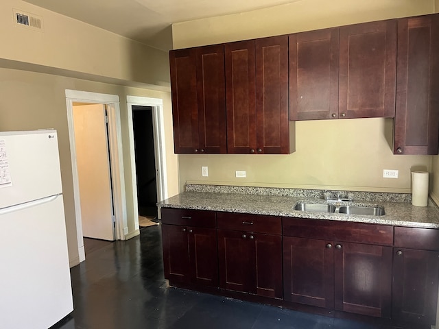 kitchen with white fridge, sink, and light stone countertops