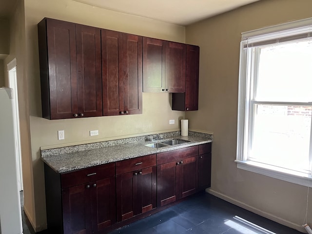 kitchen with sink, white fridge, and light stone counters