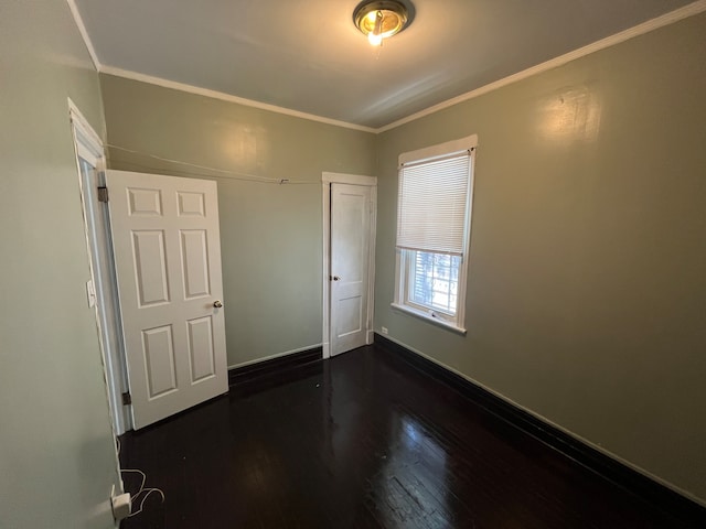 unfurnished bedroom with dark wood-type flooring, crown molding, and a closet