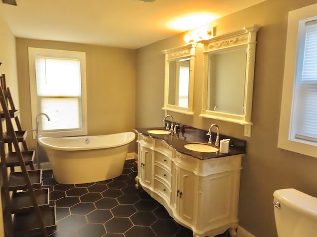 bathroom featuring vanity, tile patterned flooring, a washtub, and toilet