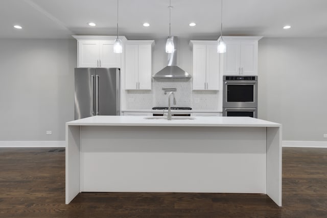 kitchen with a center island with sink, pendant lighting, white cabinetry, and appliances with stainless steel finishes