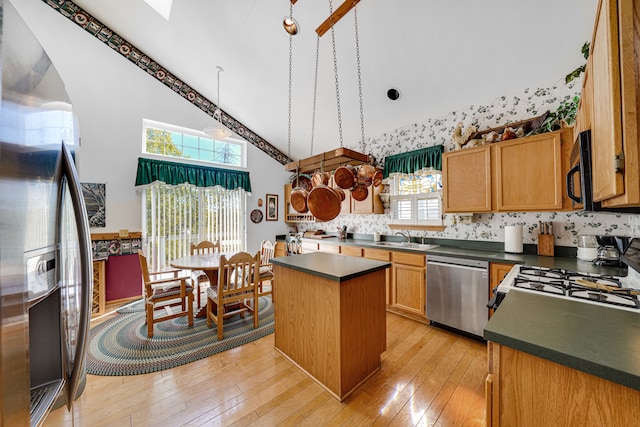 kitchen with high vaulted ceiling, stainless steel appliances, light hardwood / wood-style floors, and a kitchen island