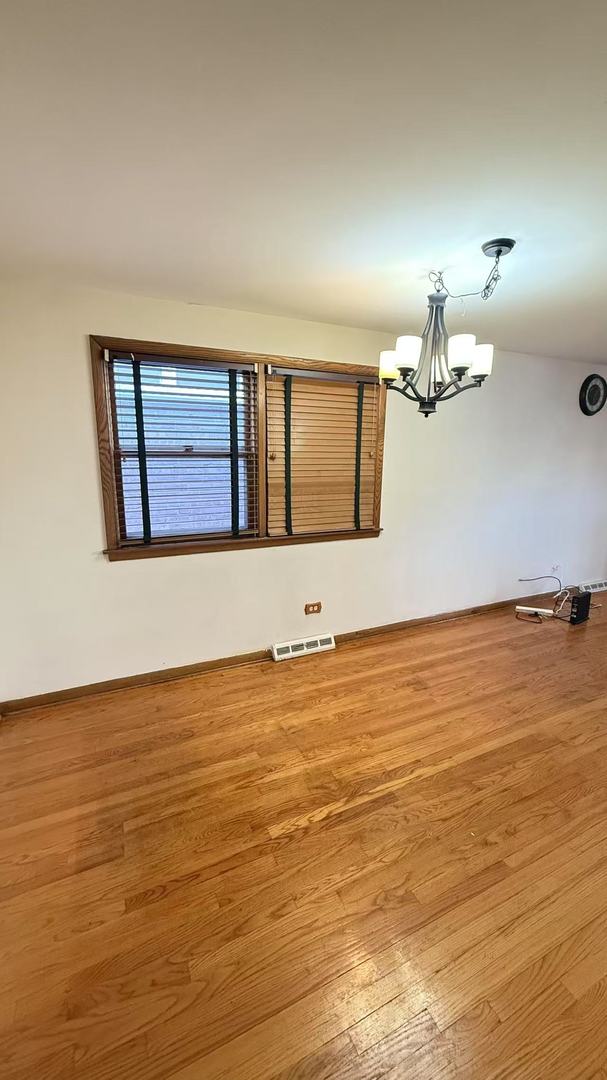 unfurnished room with a chandelier, visible vents, and wood finished floors