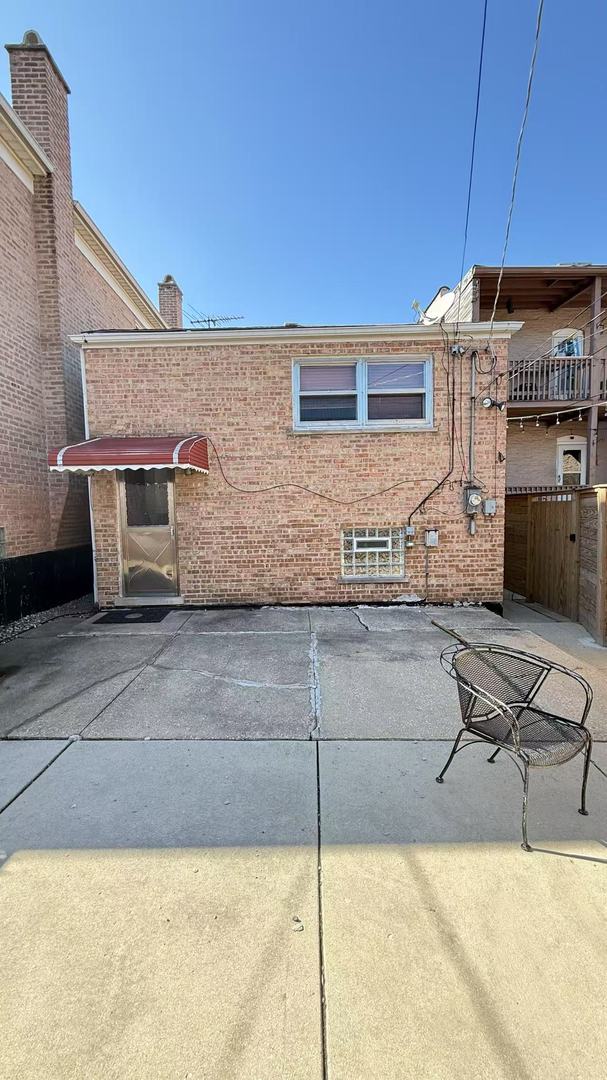 exterior space featuring brick siding, fence, and a chimney