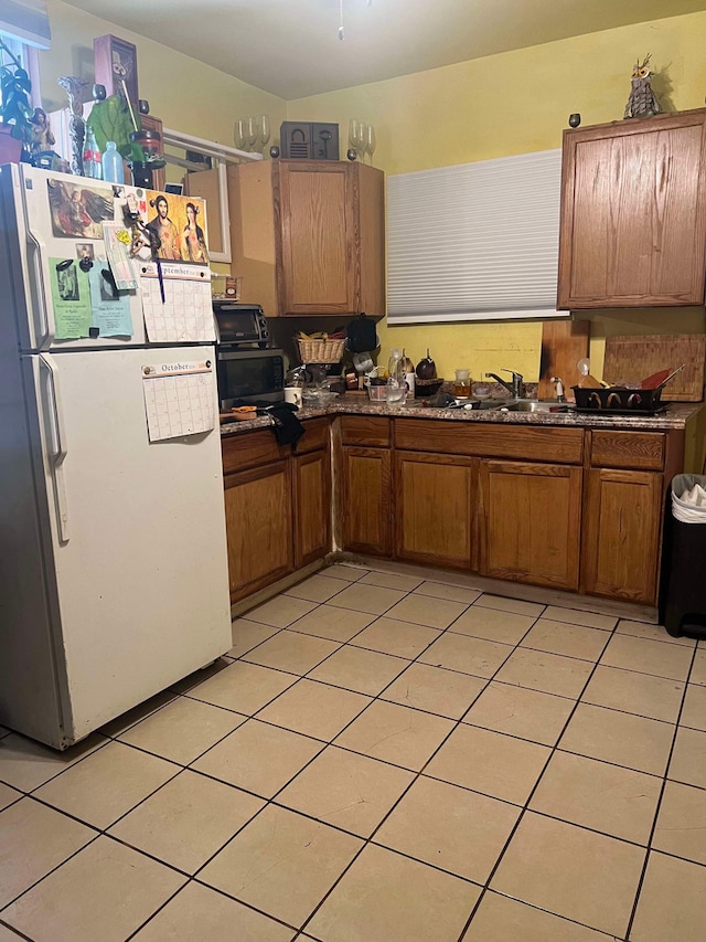 kitchen featuring white refrigerator, sink, and light tile patterned flooring