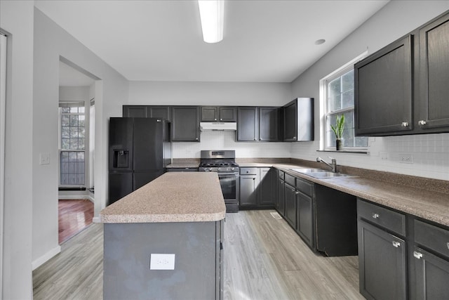 kitchen featuring sink, gas stove, a center island, black fridge, and light hardwood / wood-style floors