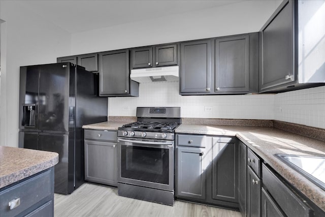 kitchen with gas stove, decorative backsplash, light wood-type flooring, black fridge with ice dispenser, and gray cabinets