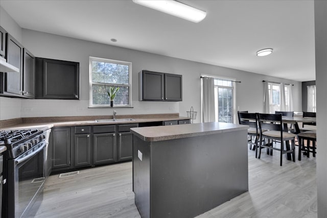 kitchen featuring gas range, light hardwood / wood-style floors, a healthy amount of sunlight, and a center island