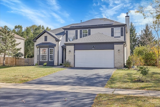 front facade featuring solar panels, a front lawn, and a garage