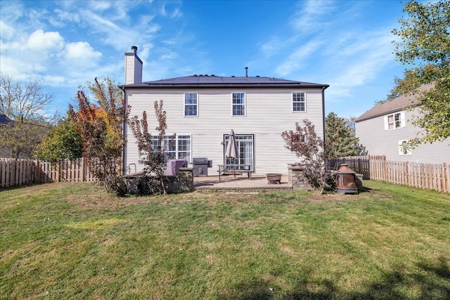 back of property featuring a patio area, a lawn, and solar panels