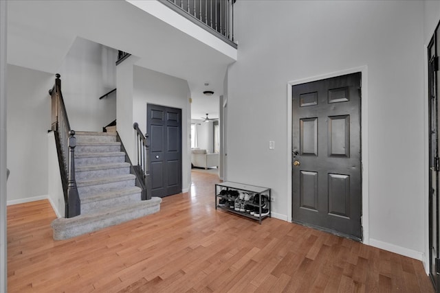 foyer entrance featuring a high ceiling, light wood-type flooring, and ceiling fan