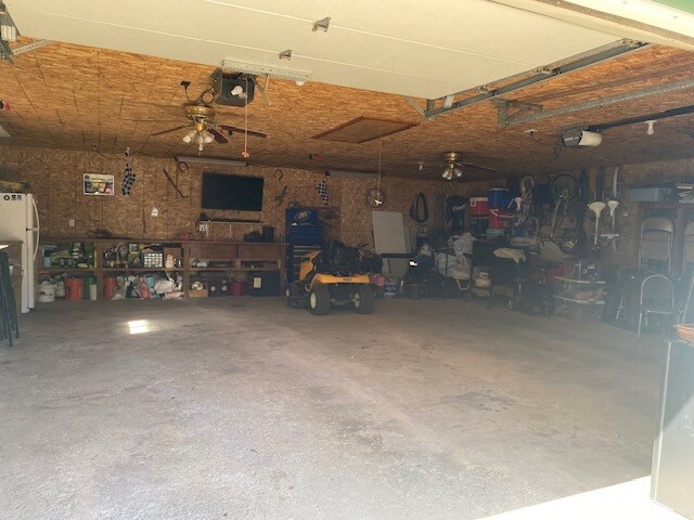 garage featuring white fridge, ceiling fan, and a garage door opener