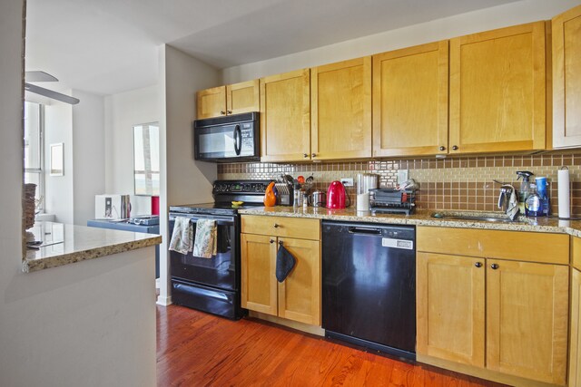 kitchen with light stone countertops, black appliances, backsplash, dark hardwood / wood-style flooring, and ceiling fan