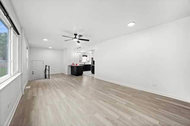 unfurnished living room featuring ceiling fan, plenty of natural light, and light wood-type flooring