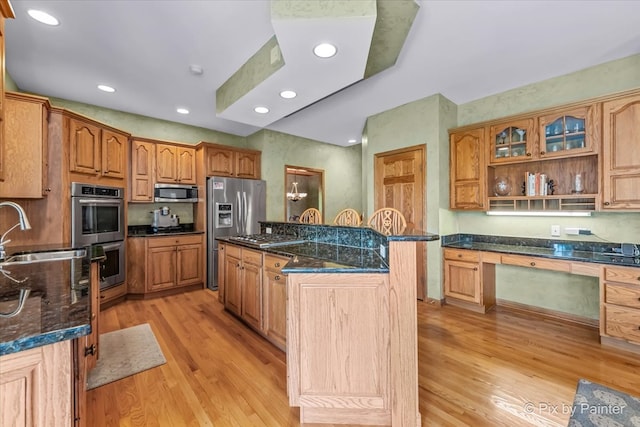 kitchen featuring stainless steel appliances, dark stone counters, sink, a center island, and light hardwood / wood-style floors