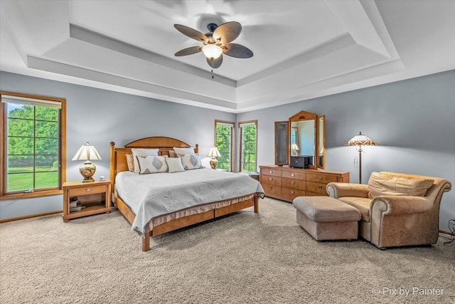 bedroom featuring multiple windows, a tray ceiling, and ceiling fan