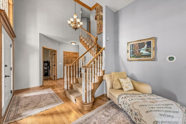 foyer entrance with an inviting chandelier, a high ceiling, and light wood-type flooring