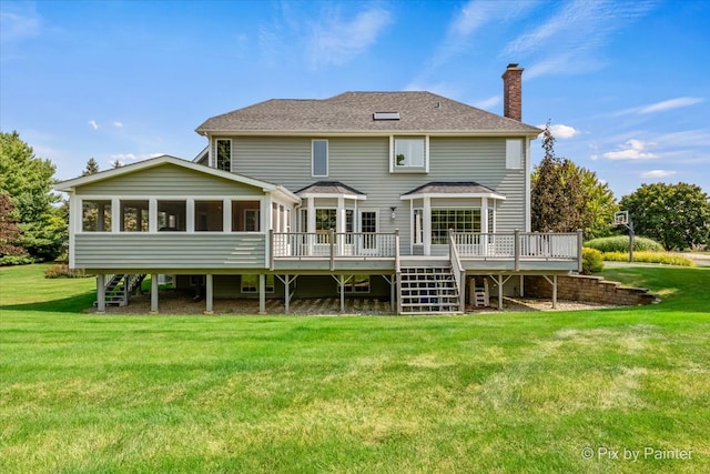 rear view of property with a deck, a lawn, and a sunroom