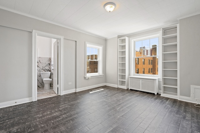 unfurnished room featuring built in shelves, crown molding, dark hardwood / wood-style floors, and radiator