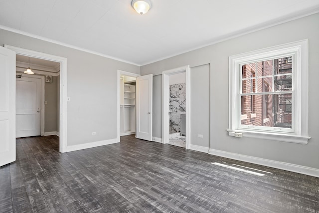 unfurnished bedroom featuring ornamental molding, a walk in closet, dark hardwood / wood-style floors, and ensuite bath