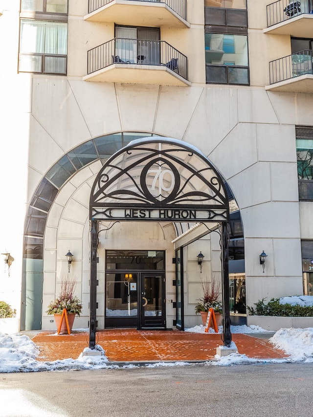 snow covered property entrance with a balcony