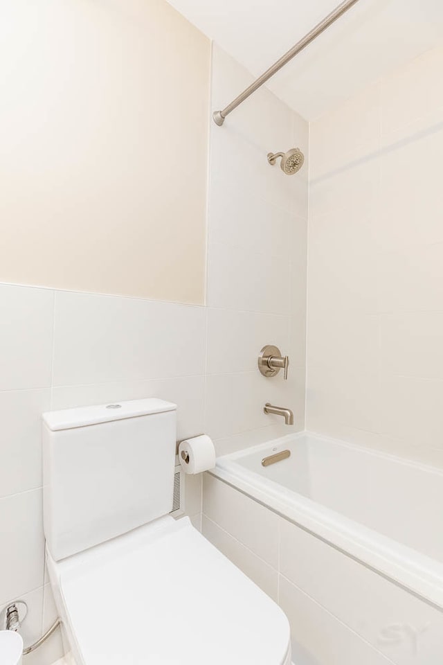 bathroom with toilet, tile walls, and tiled shower / bath