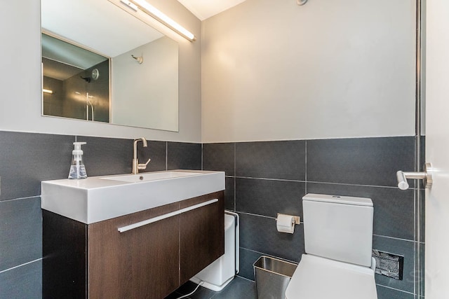 bathroom with toilet, vanity, and tile walls