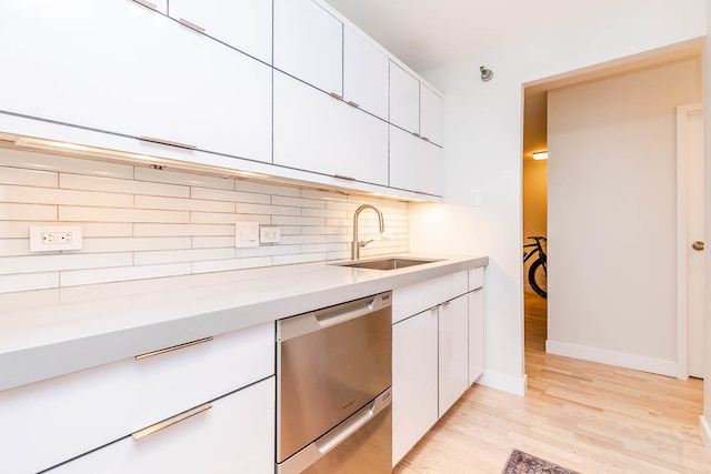 kitchen with white cabinets, backsplash, stainless steel dishwasher, light hardwood / wood-style flooring, and sink